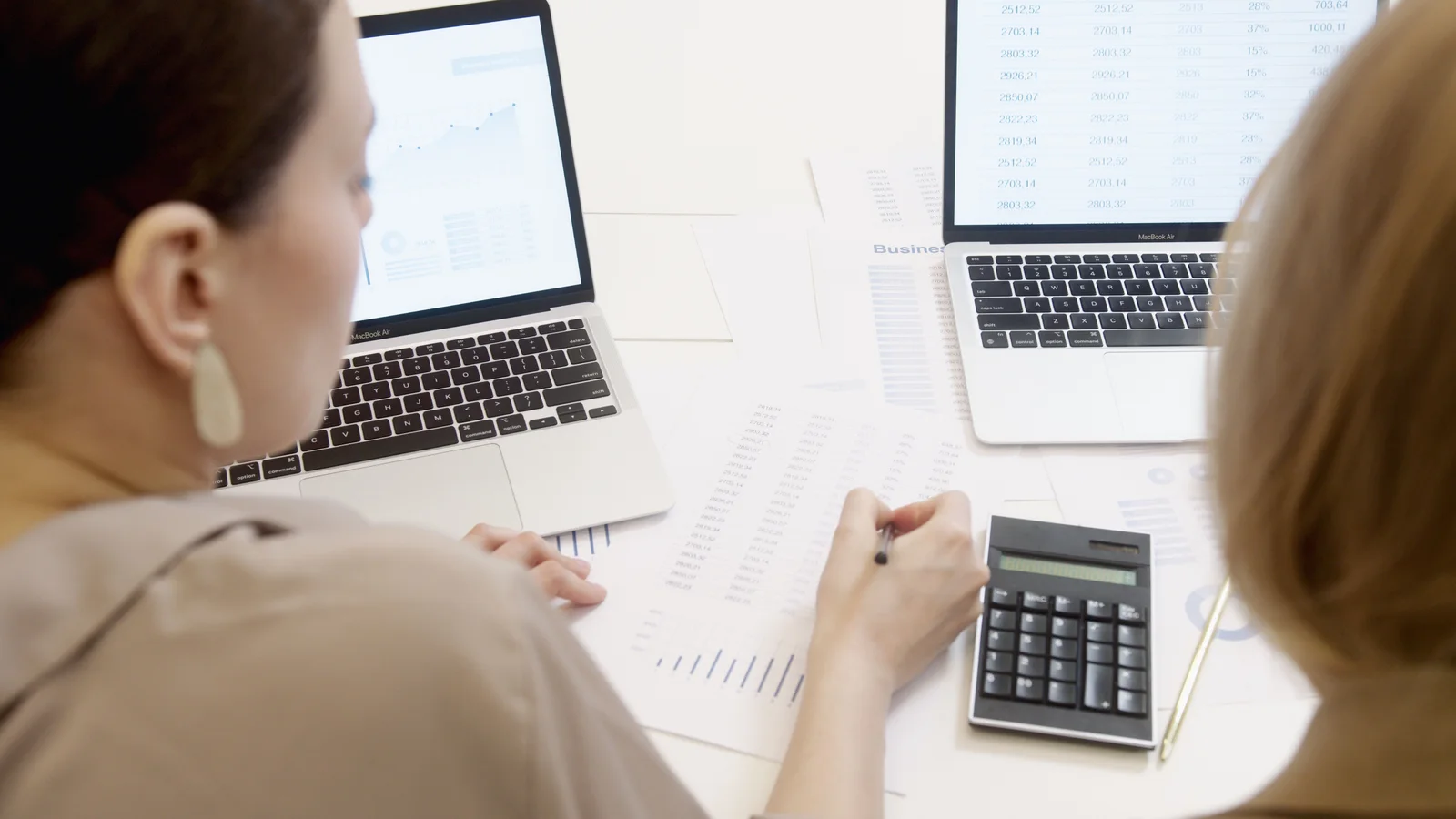 Two people reviewing reports and laptop data, illustrating SEO recovery analysis